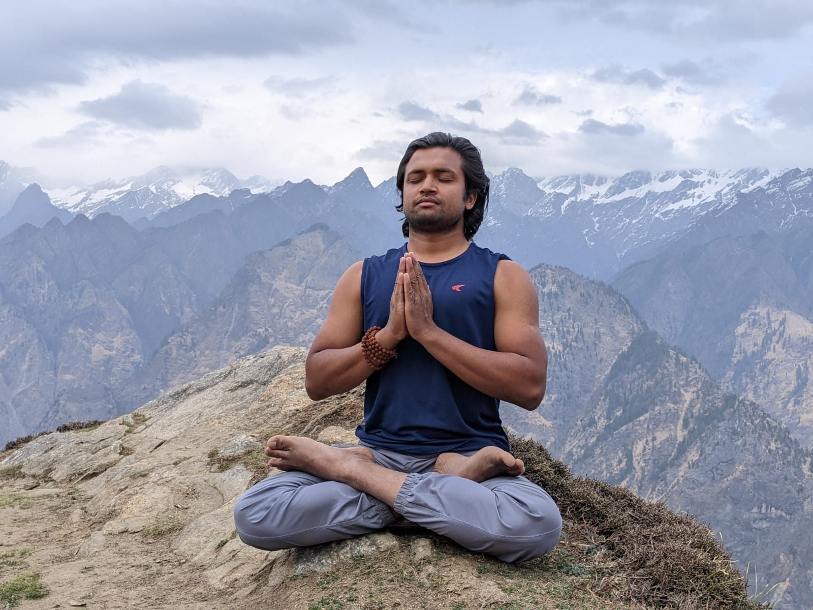 Yogi Gajendra in seated meditation outdoors, hands folded in namaste